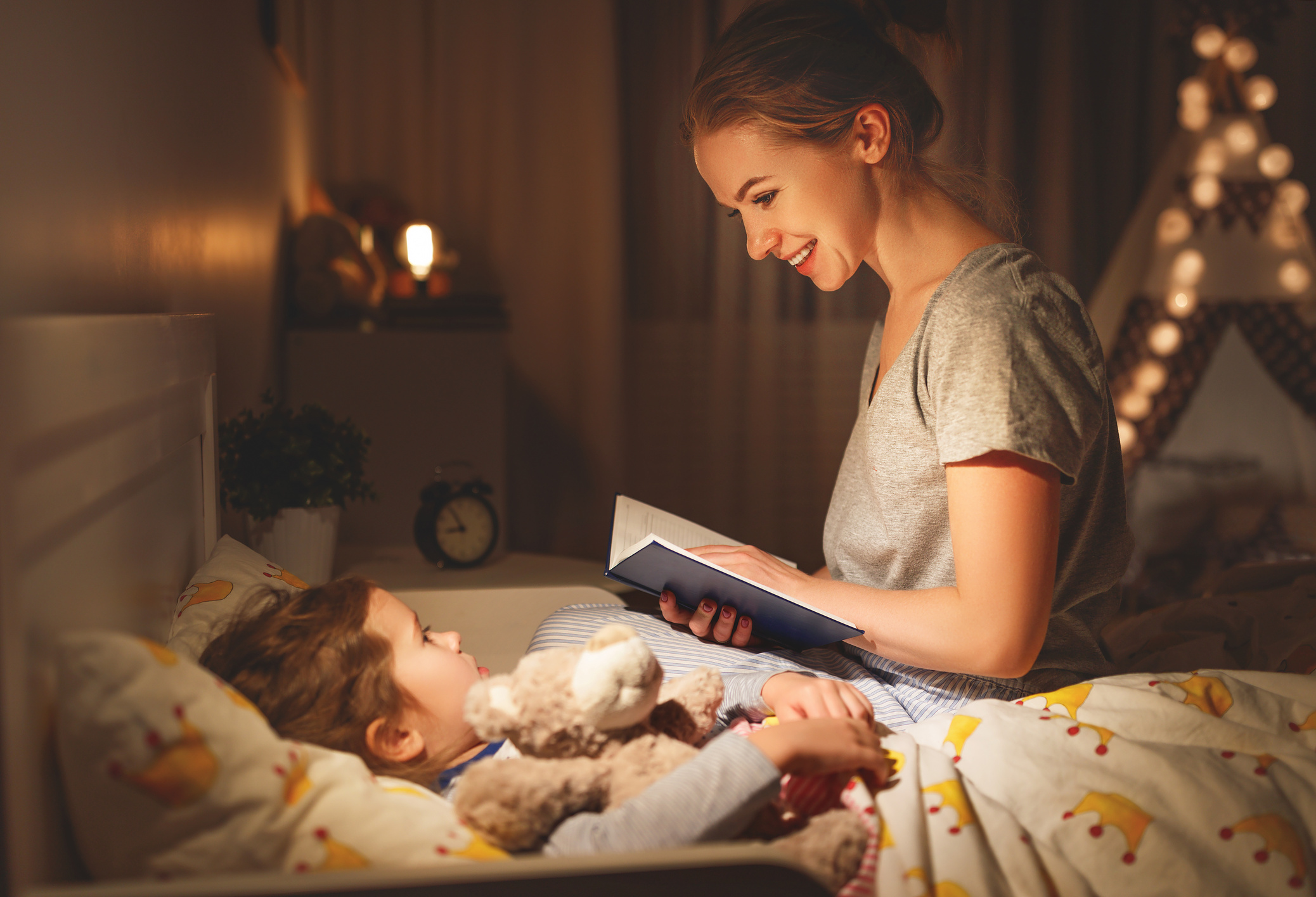 mother and child reading book in bed before going to sleep